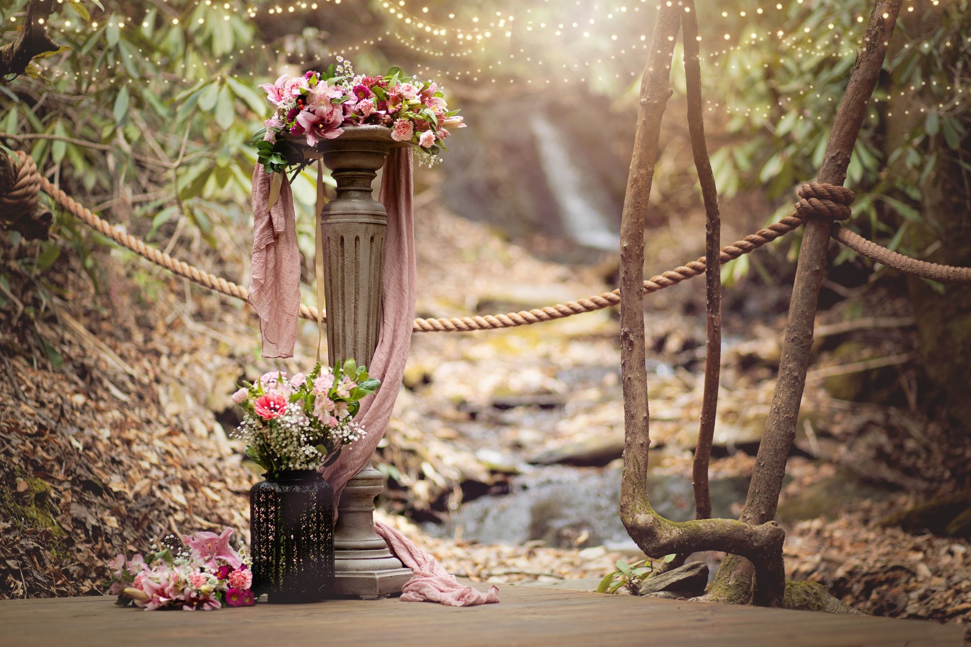 Two wedding vow books with pink ribbons and seals on a wooden table with flowers.