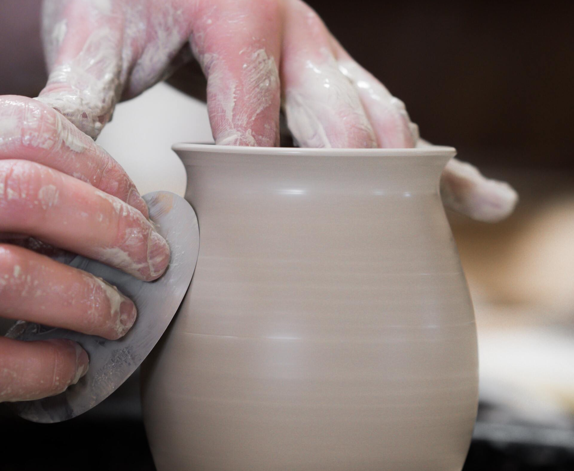 a person is making a vase on a pottery wheel .