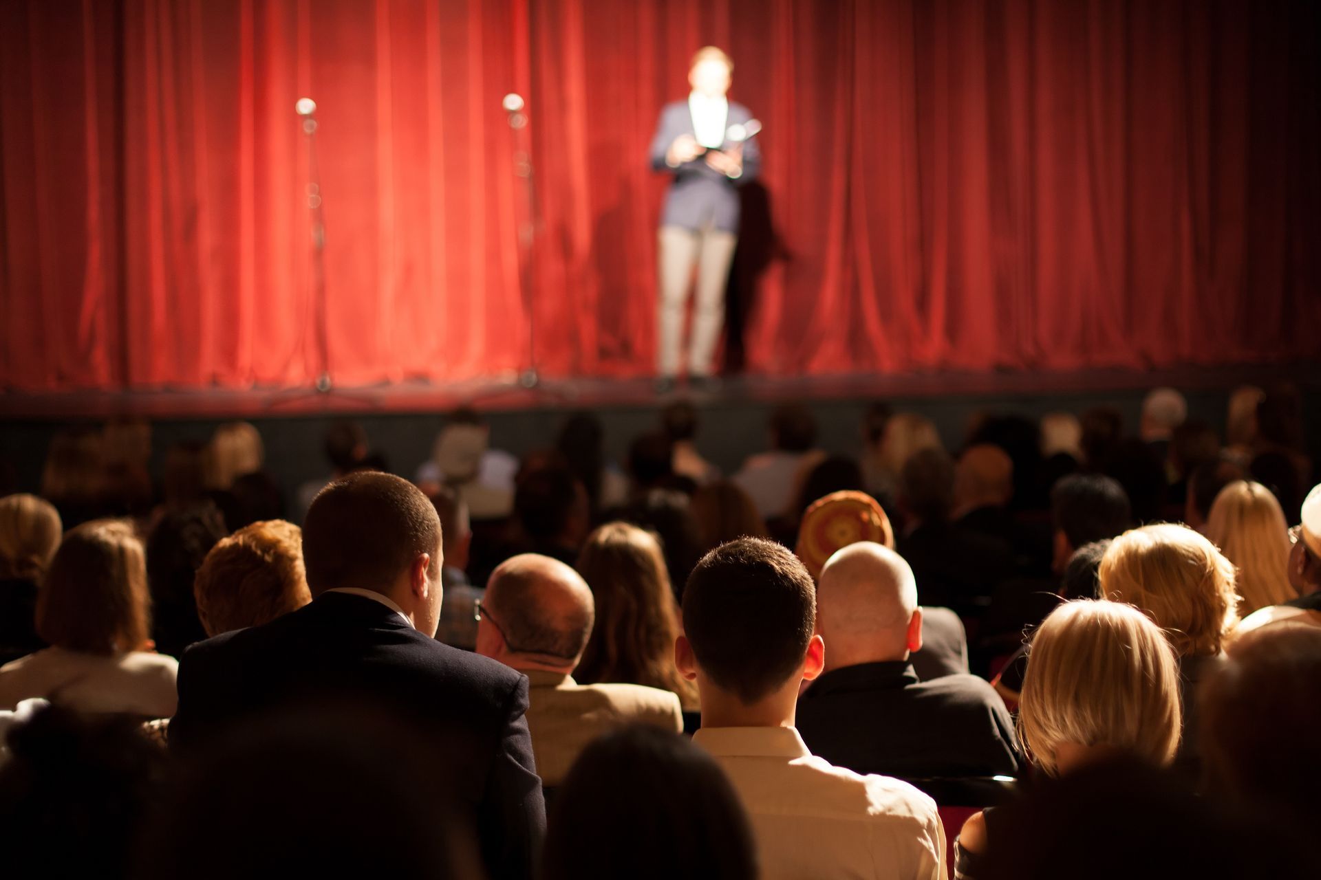 A man is standing on a stage in front of a crowd of people.