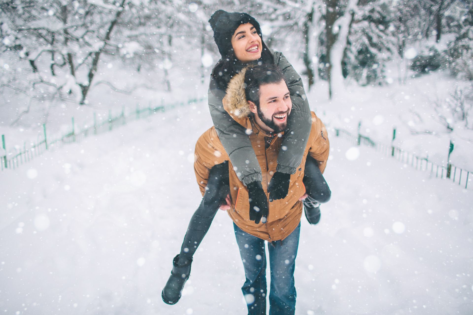 A man is carrying a woman on his back in the snow.