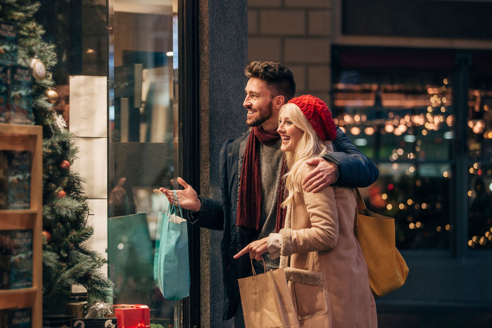 A man and a woman are looking at a christmas window display.