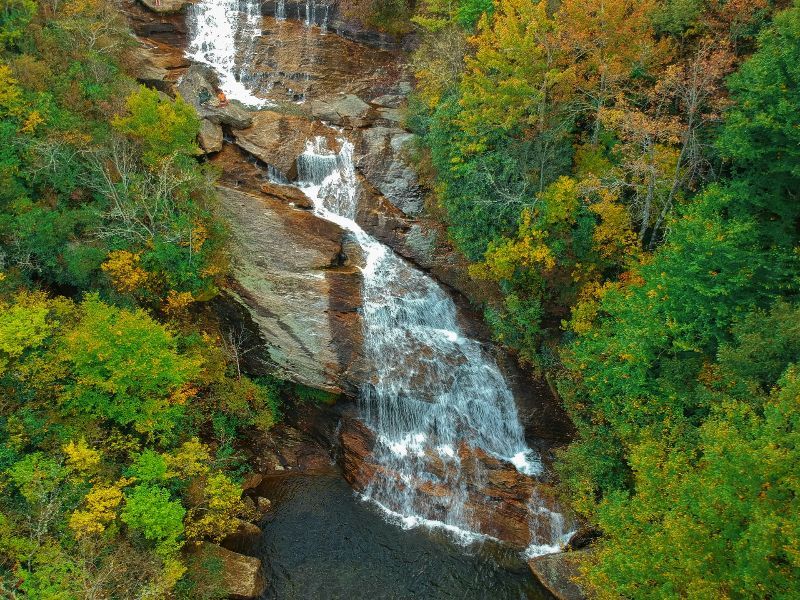 An aerial view of a waterfall in the middle of a forest.
