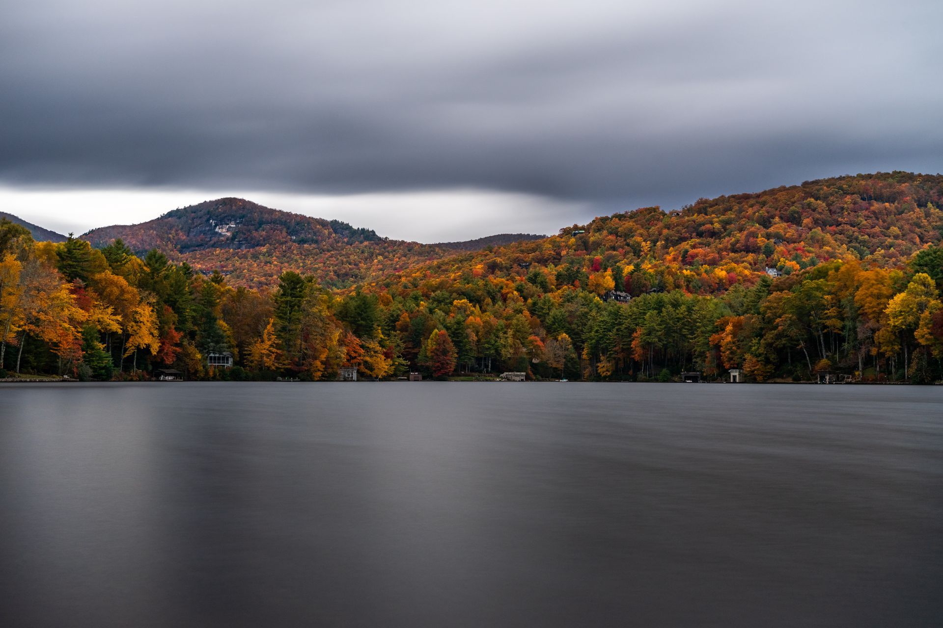 There is a lake in the middle of a forest with mountains in the background.