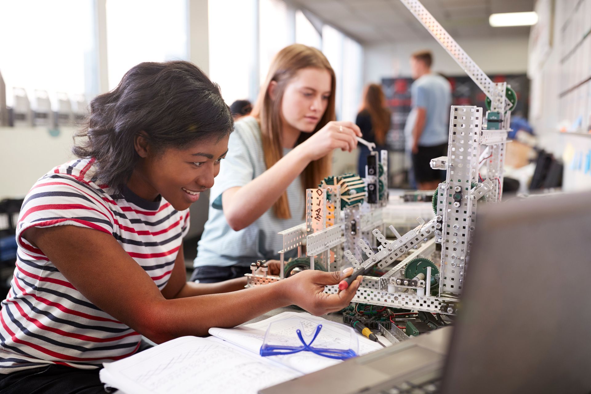 A boy and a girl are working on a robot together.