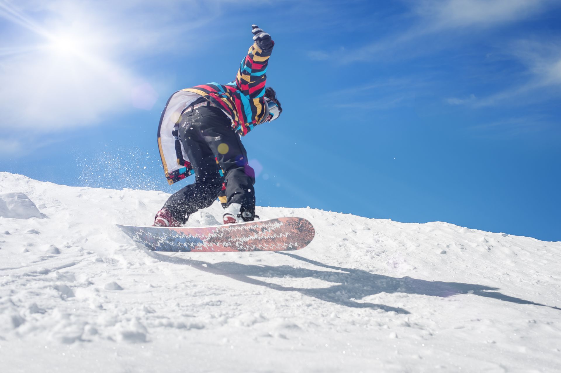 A person is riding a snowboard down a snow covered hill.