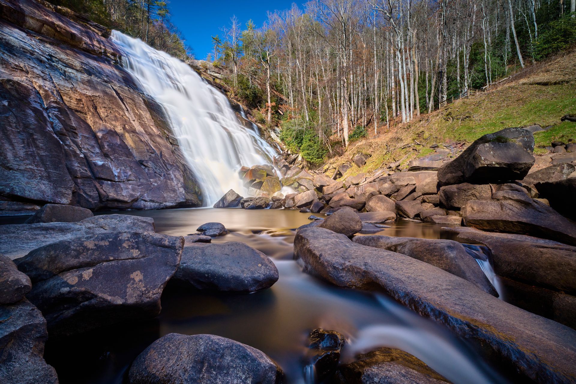 A waterfall is surrounded by rocks and trees in the middle of a forest.