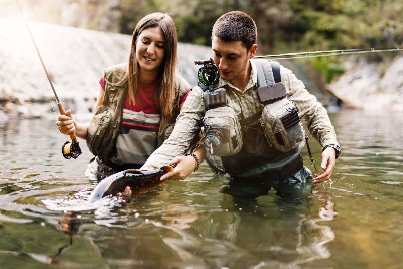 A man and a woman are fishing in a river.