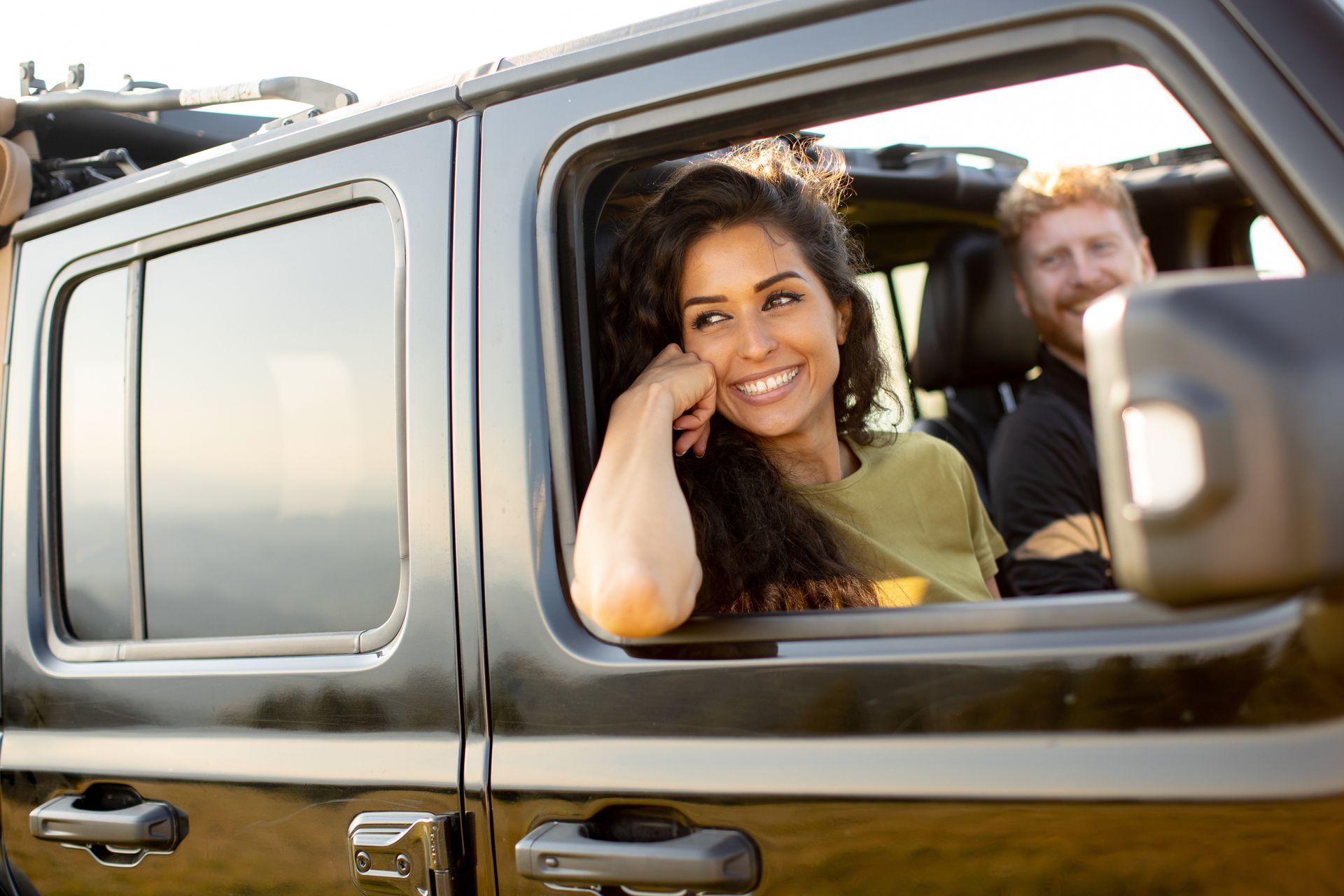 A woman is looking out of the window of a jeep.