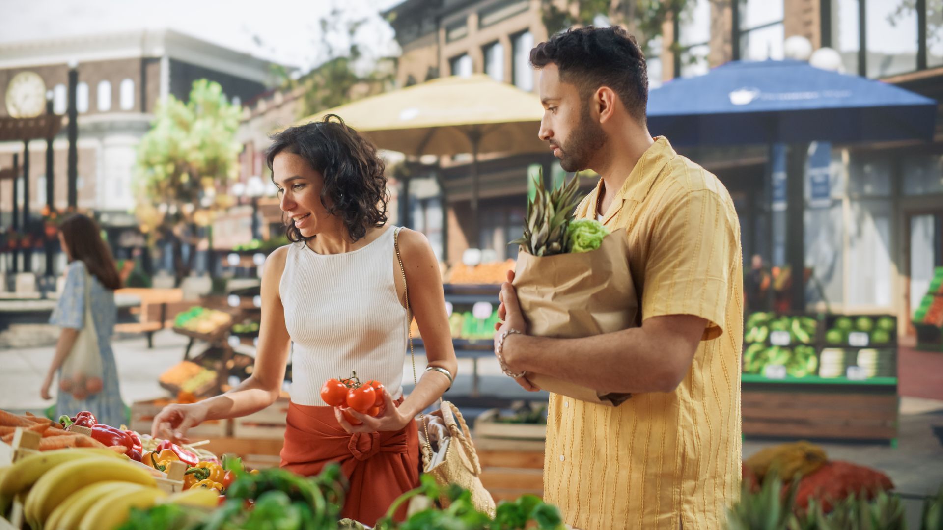 A man and a woman are shopping at a farmers market.