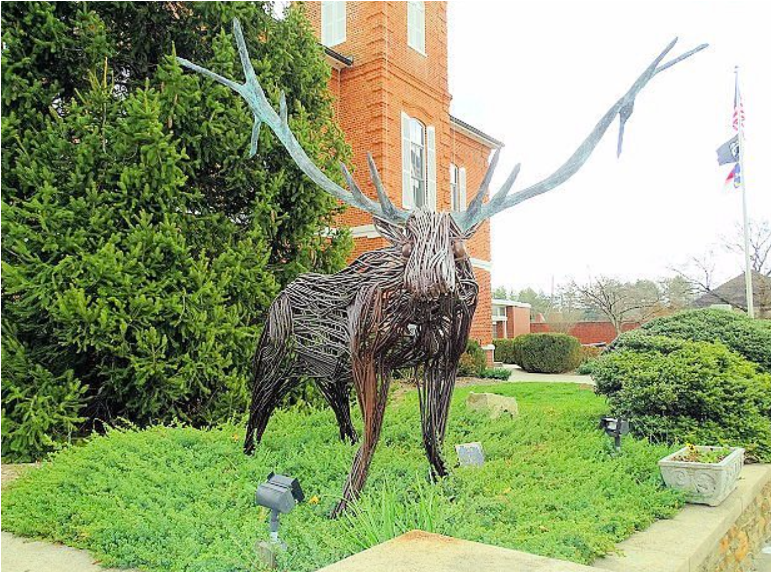 a statue of a deer with antlers is in front of a brick building