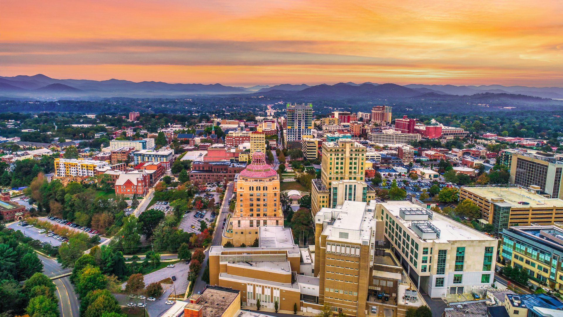 an aerial view of a city at sunset with mountains in the background .