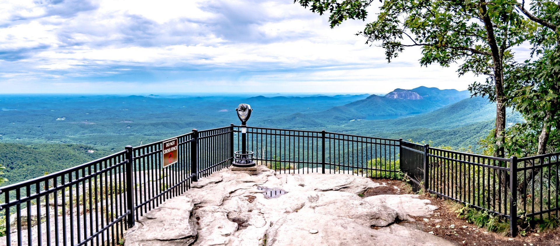 A viewpoint on top of a mountain with a fence and binoculars.