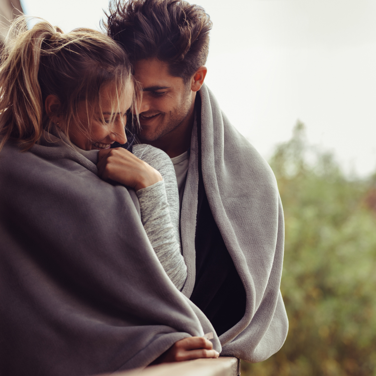 A man and a woman are wrapped in a blanket