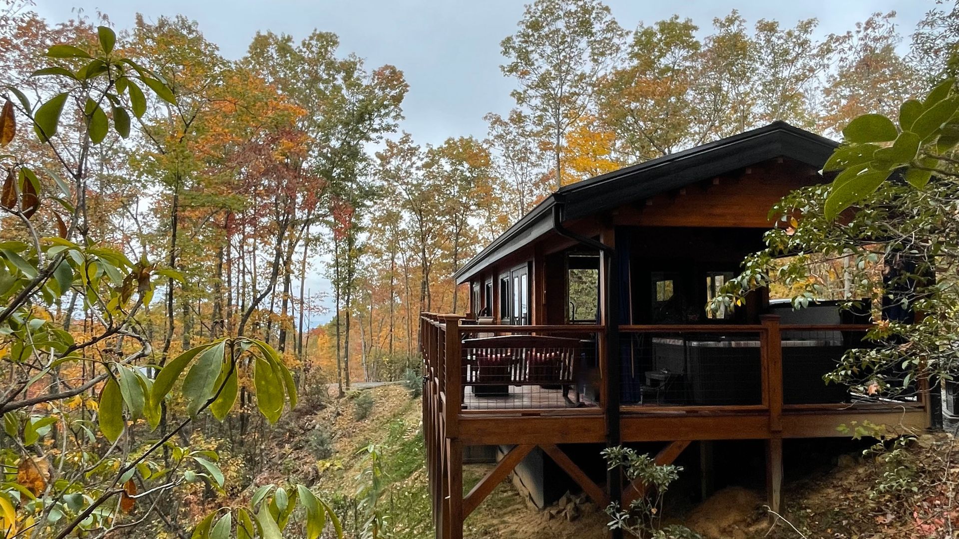A kitchen in a log cabin with a black refrigerator , stove , sink and dishwasher.