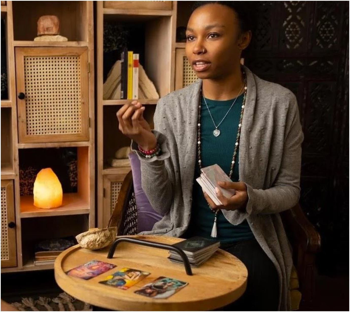A woman is sitting at a table with tarot cards on it.