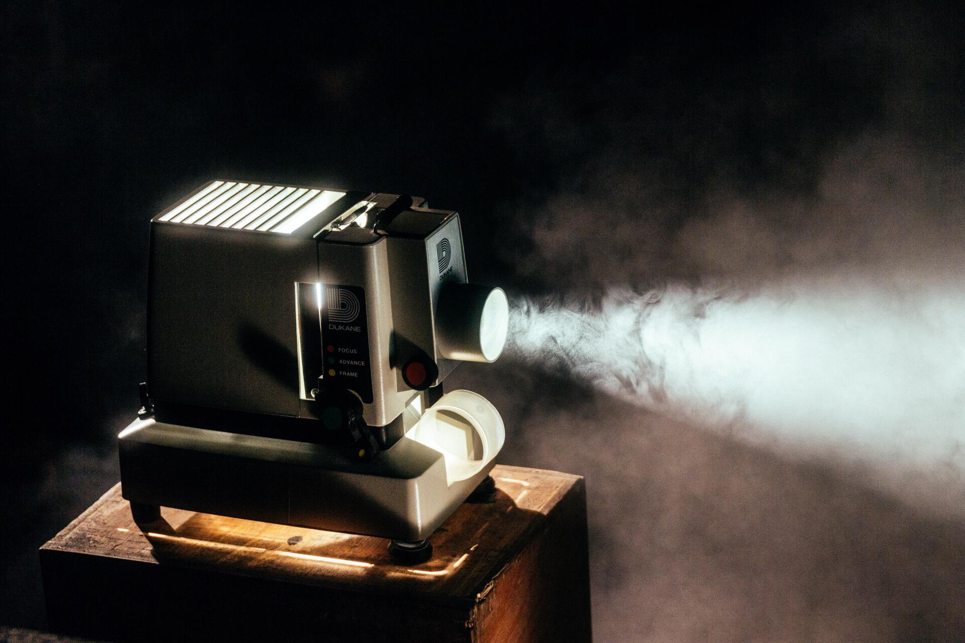 A projector is sitting on top of a wooden box with smoke coming out of it.