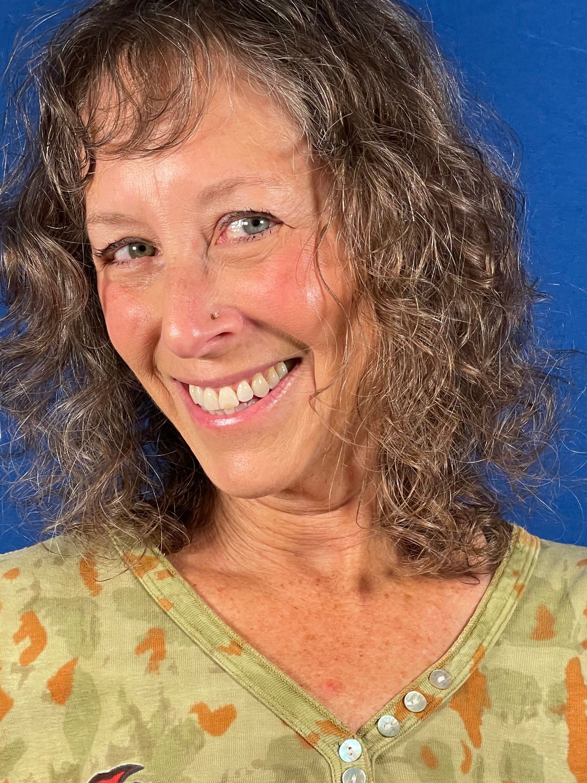 A woman wearing glasses and a red scarf is smiling in front of a crowd of people.