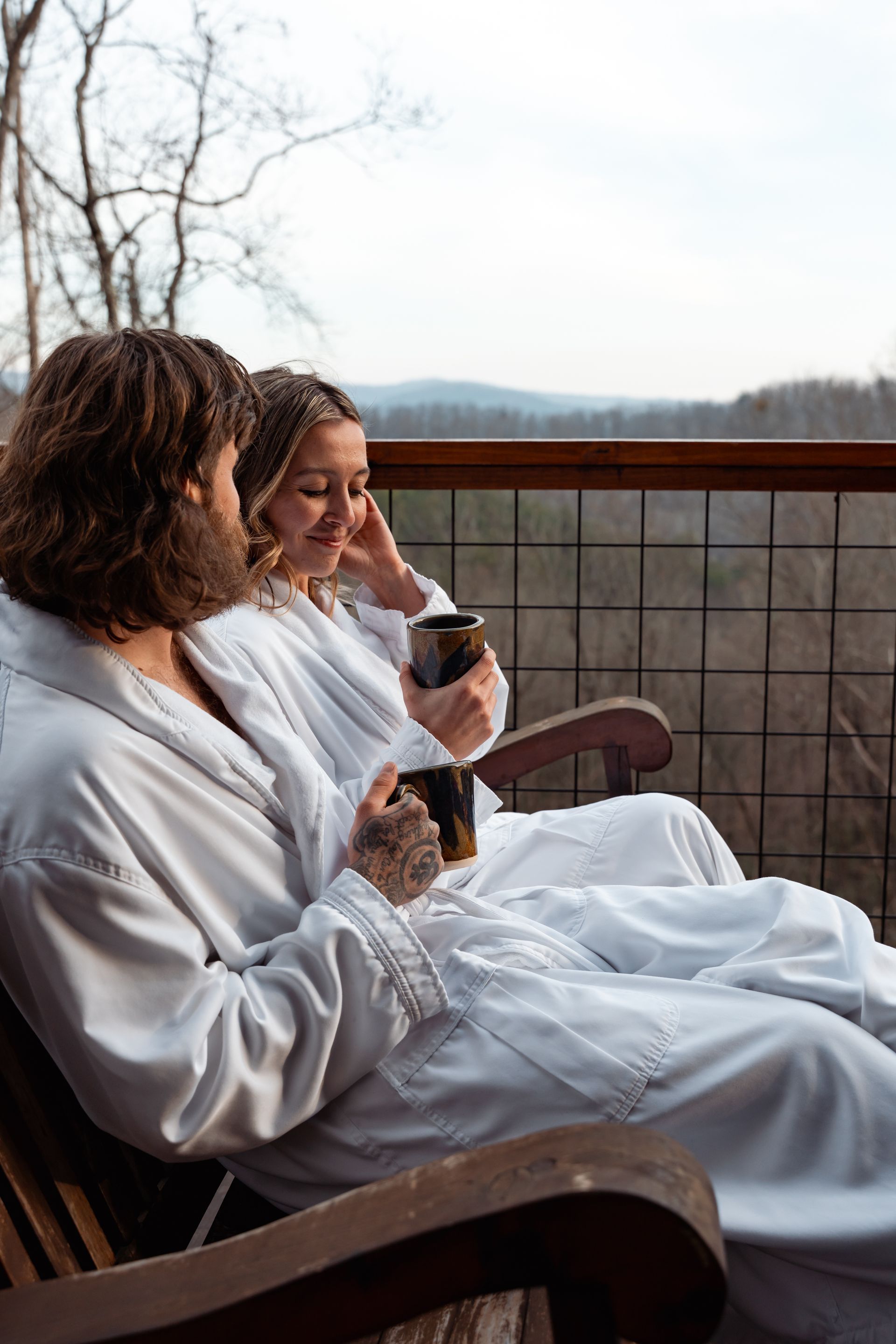 Couple seated at a table outdoors, surrounded by foliage and fairy lights.