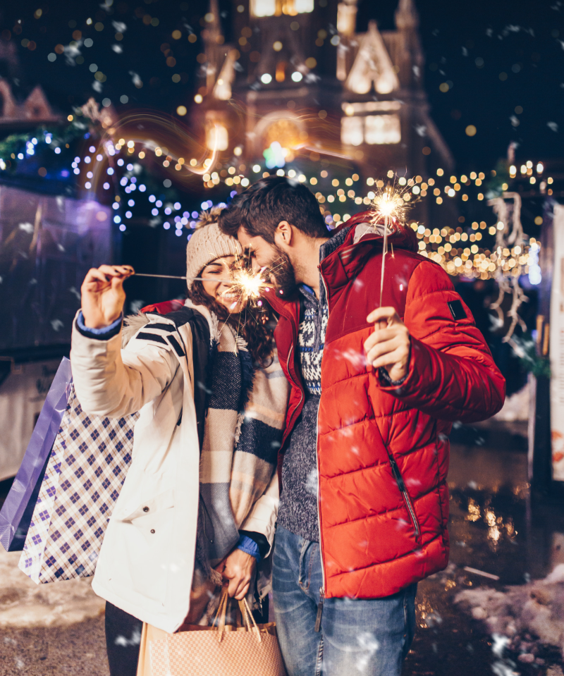 A man and a woman are holding sparklers in their hands.