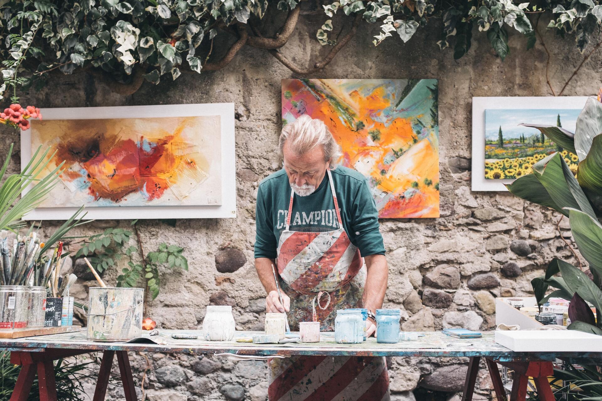 a man is painting a picture on a table in front of a stone wall .