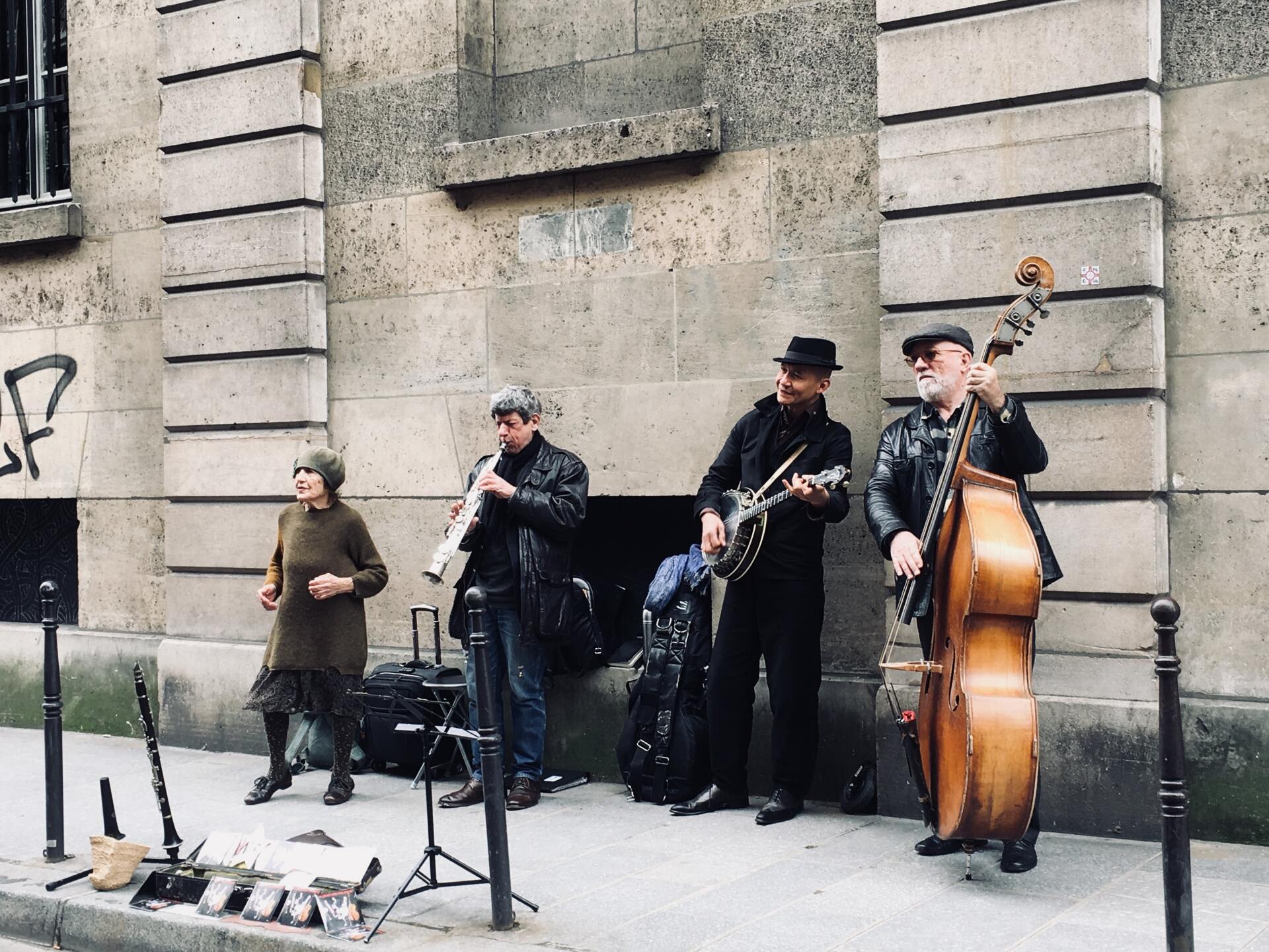 A group of musicians are playing on the sidewalk in front of a building