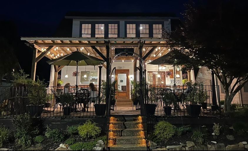 a house with a porch and umbrellas is lit up at night .