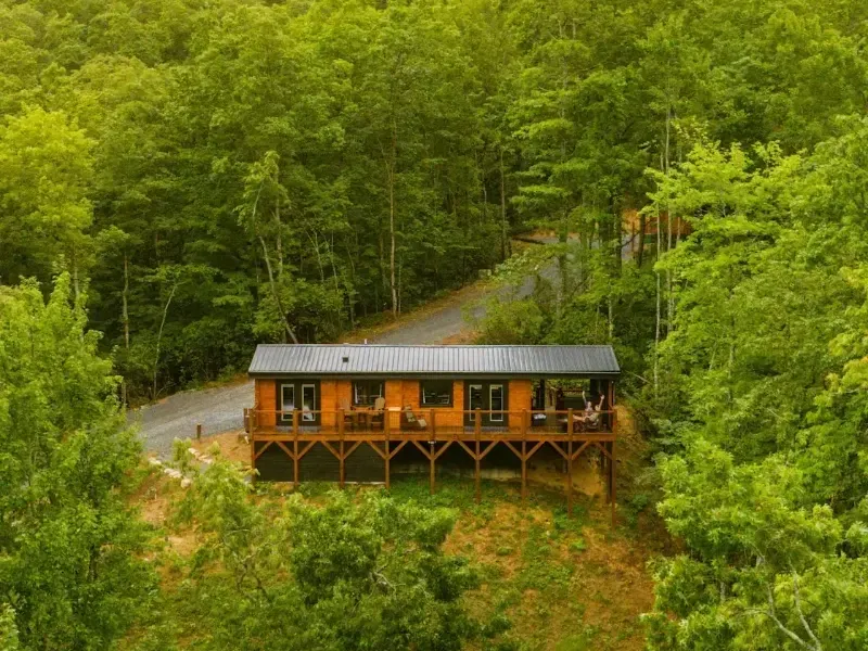 An aerial view of a cabin in the middle of a forest.