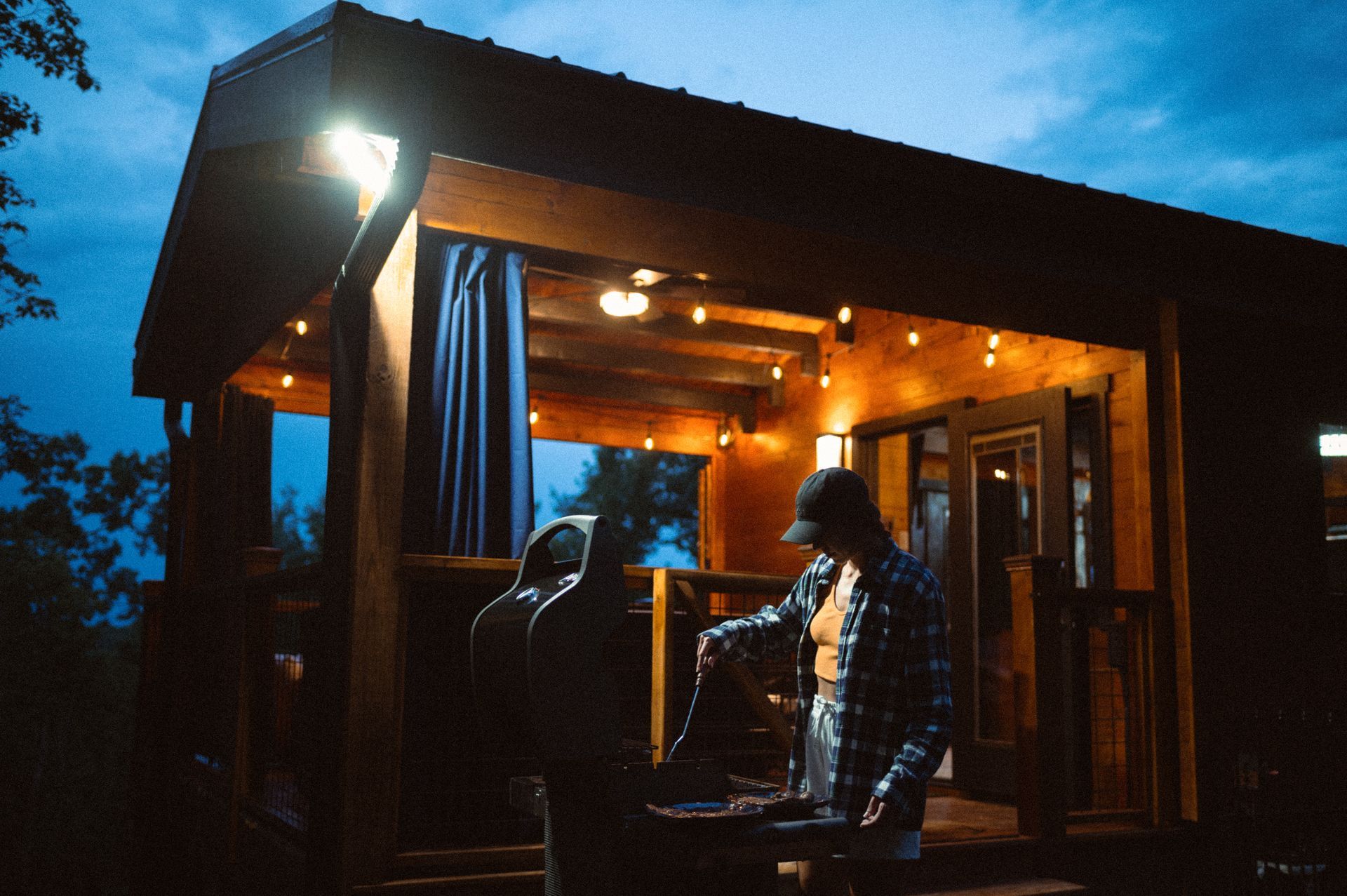 A woman is standing outside of a small house at night in her luxury cabin in brevard nc