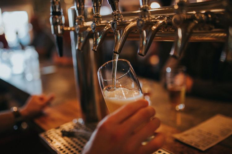 a person is pouring beer into a glass at a bar .