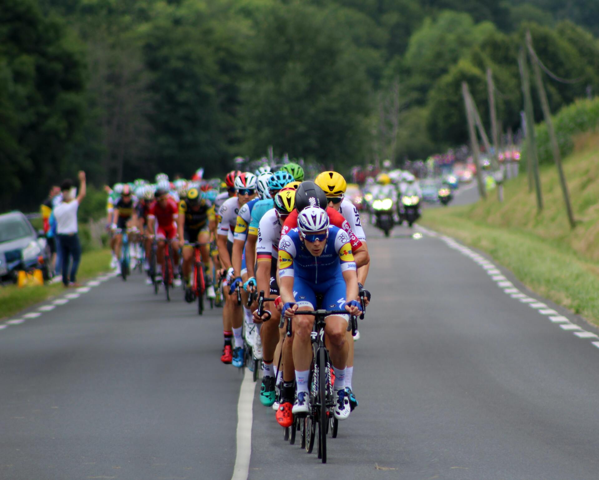 a group of cyclists are riding down a road .
