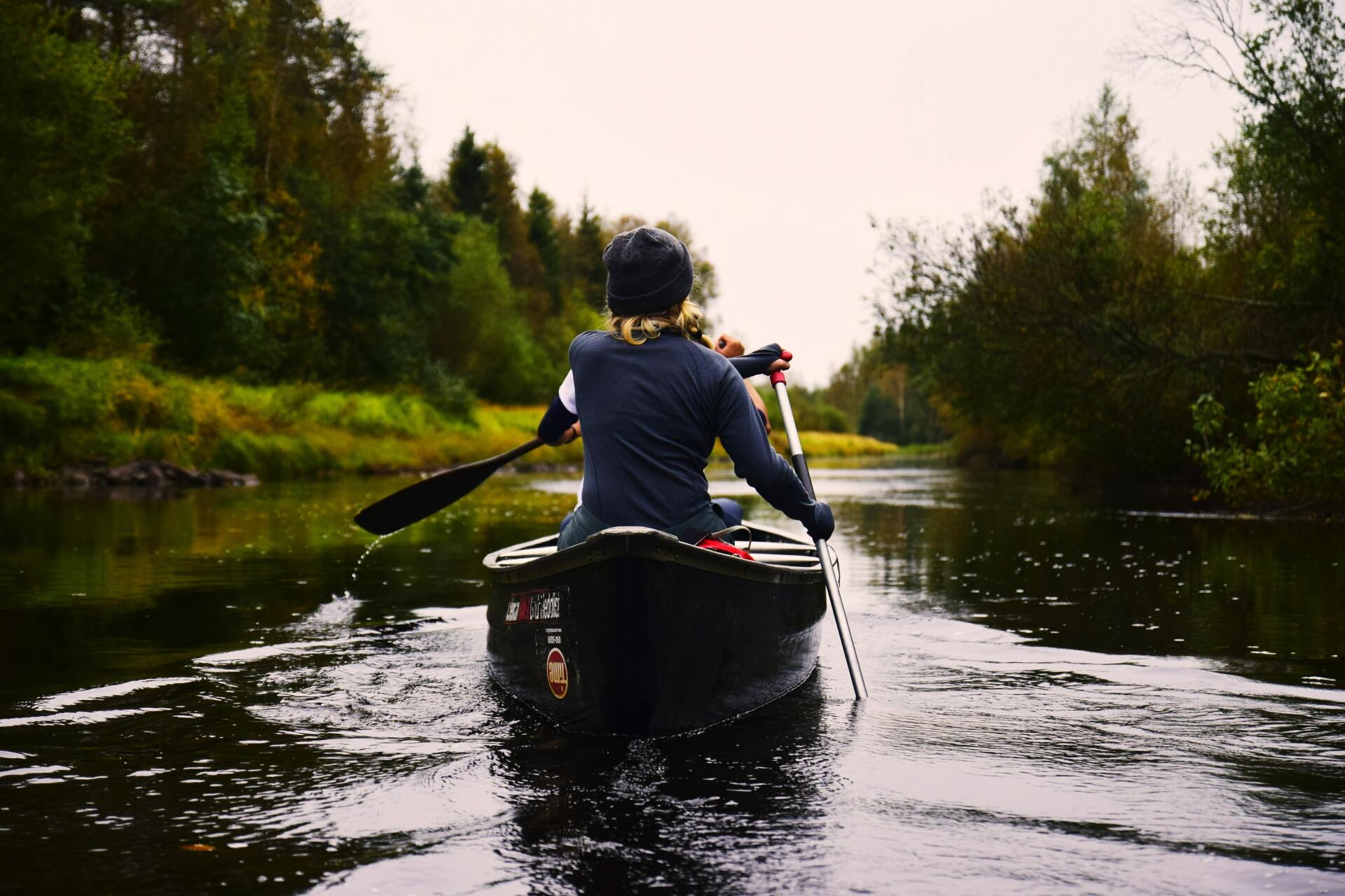 a person is paddling a canoe down a river .