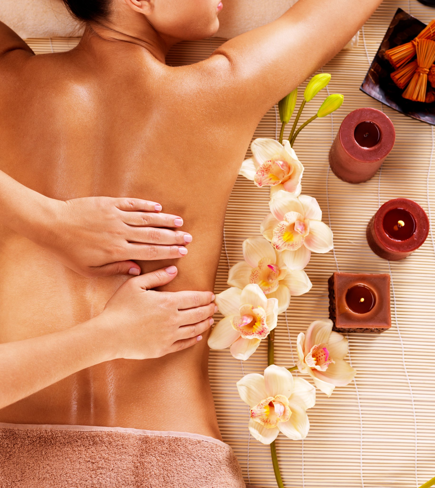 a woman is getting a massage with flowers and candles around her
