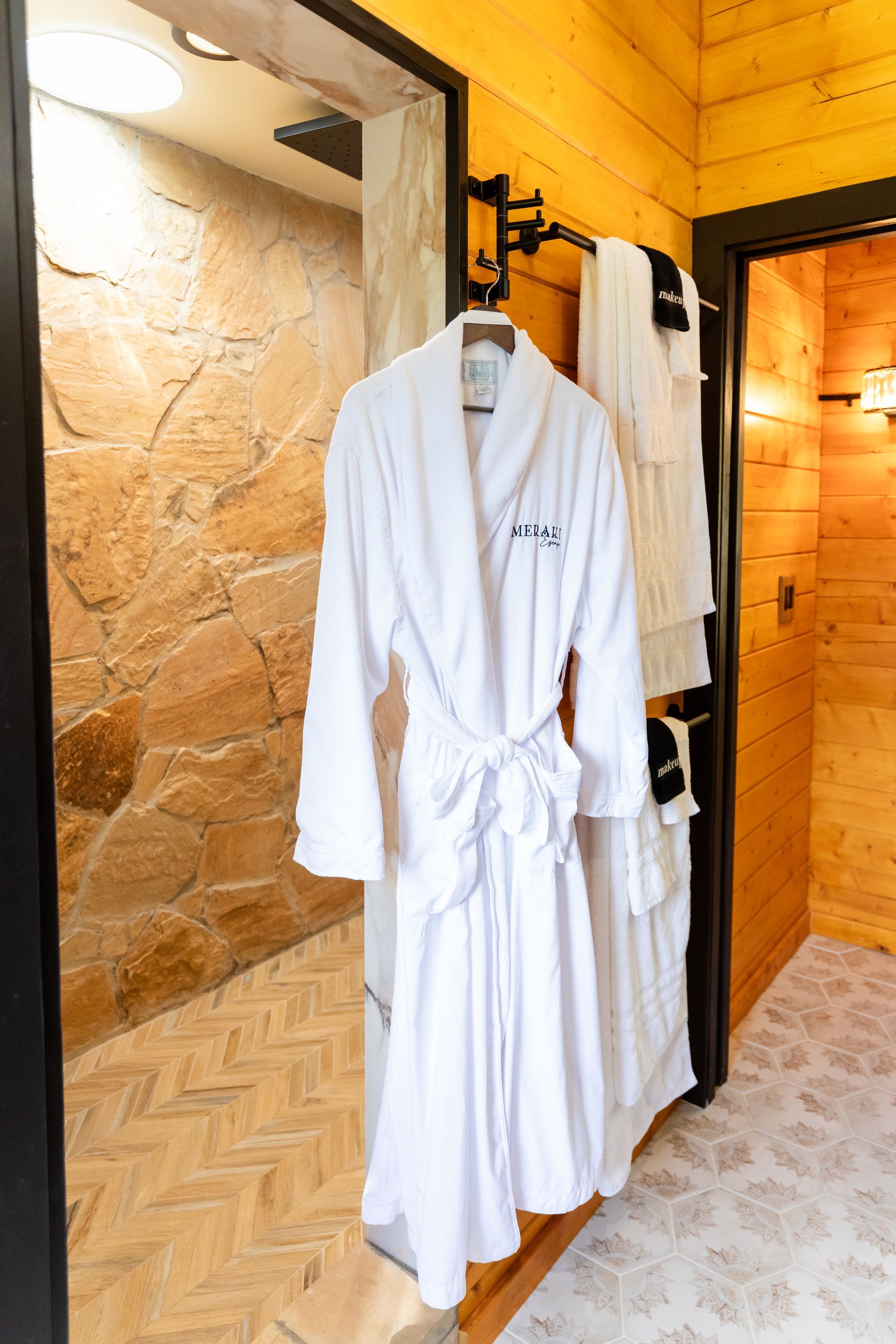 White bathrobe hanging in a rustic spa-like room with stone walls and wood trim