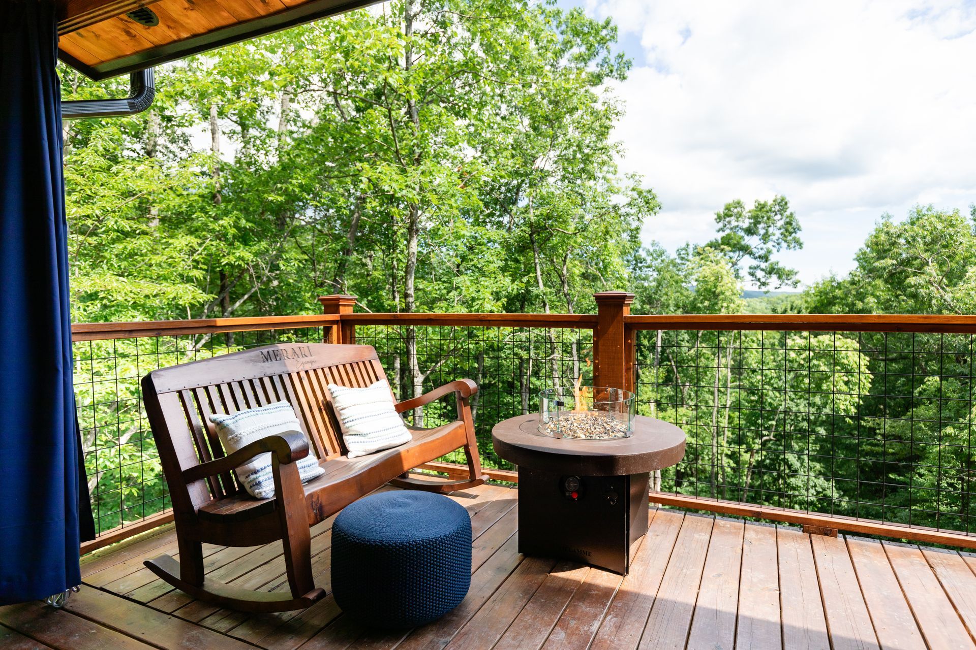 A wooden deck with a rocking bench and a fire pit.