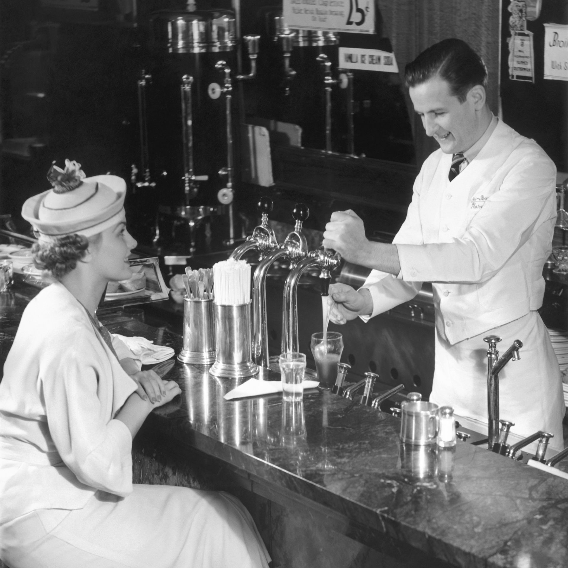 a black and white photo of a bartender pouring a drink