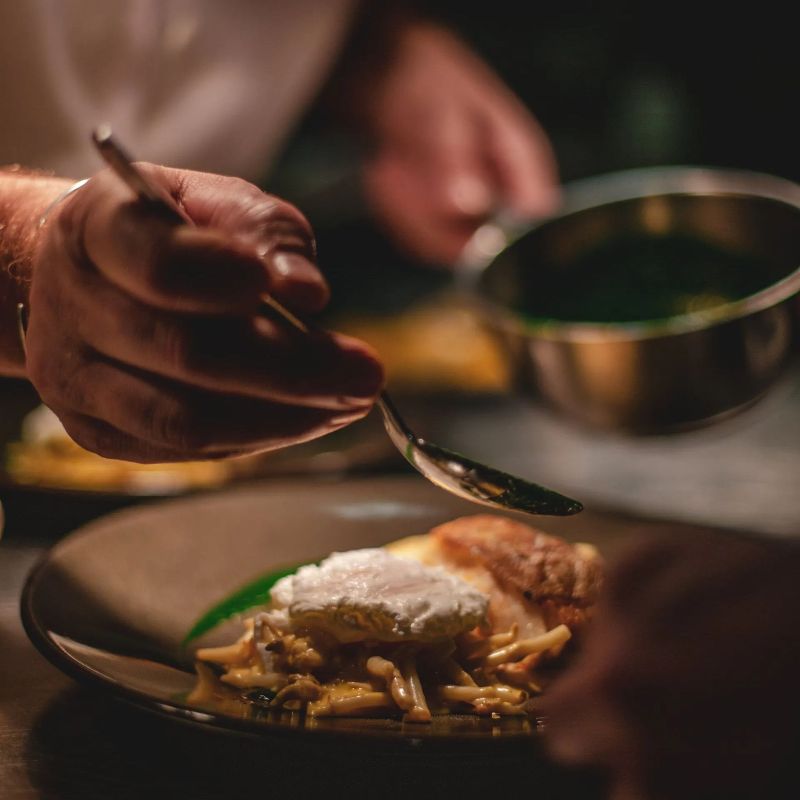 A person is holding a spoon over a plate of food