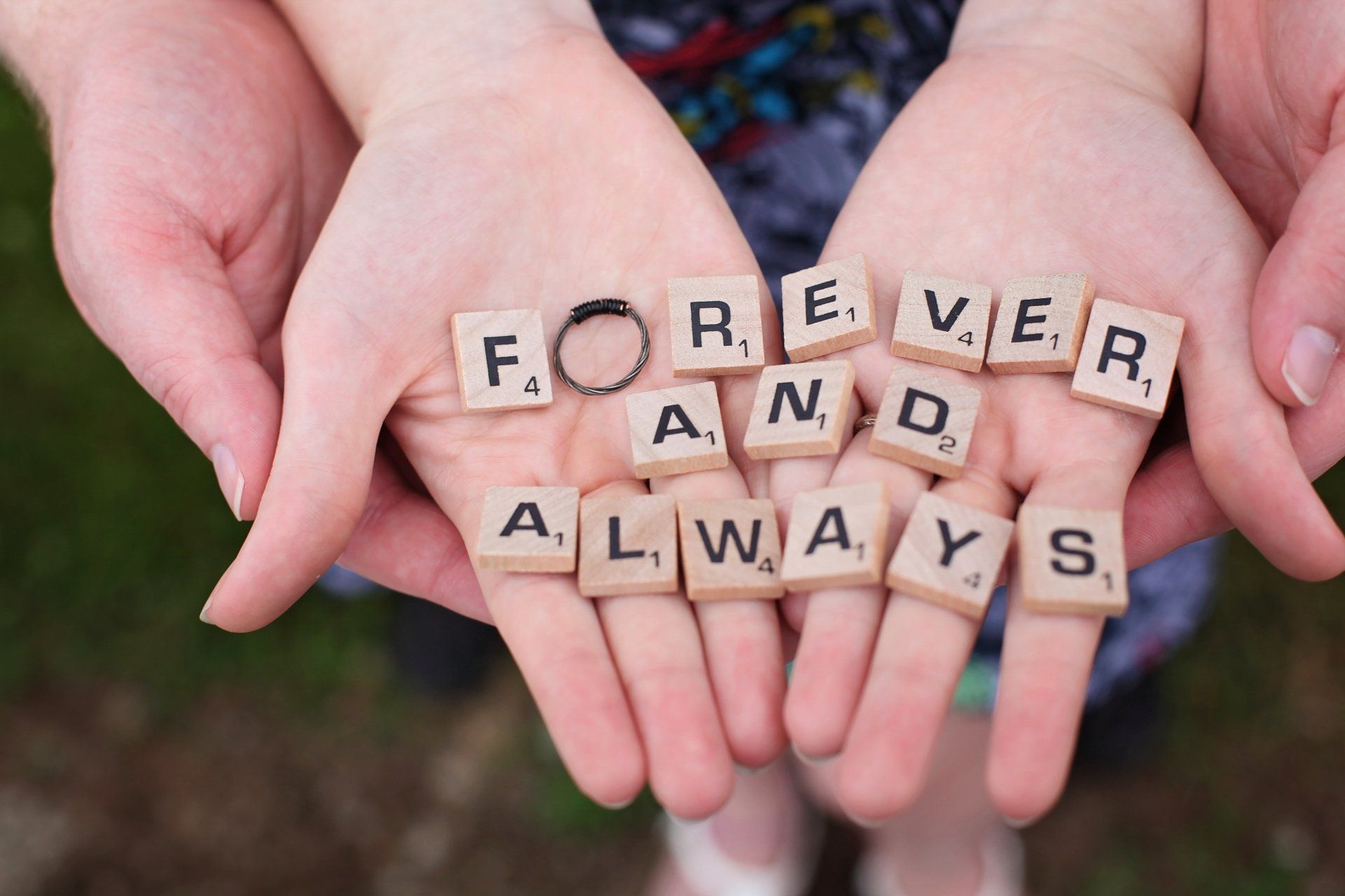 A person is holding scrabble tiles in their hands that say forever and always.