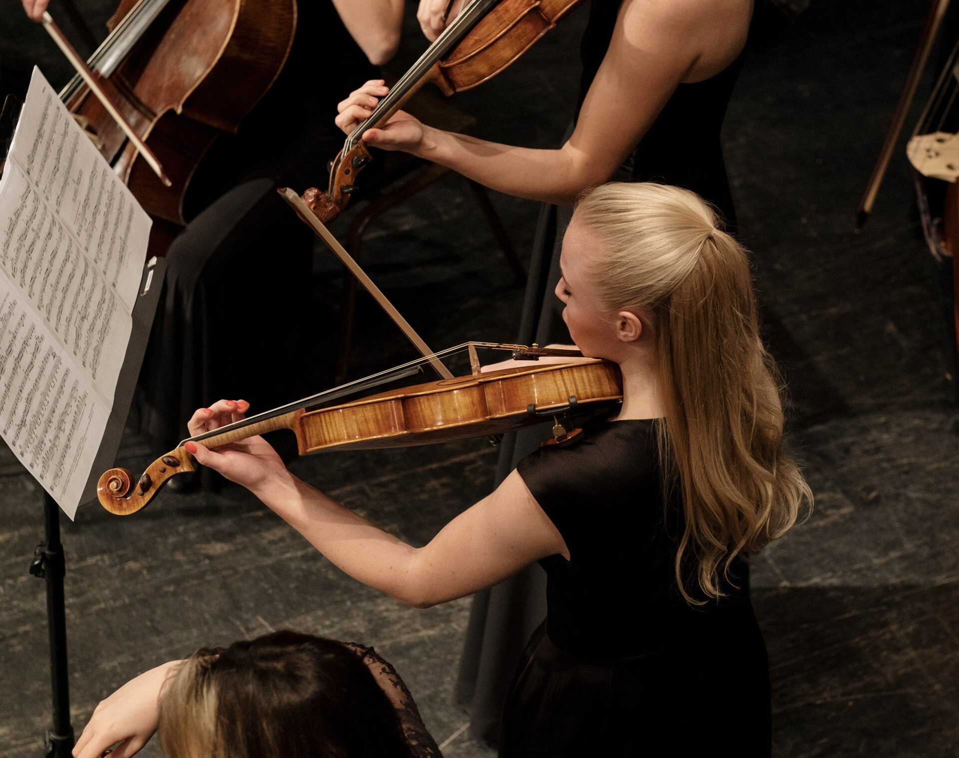 a woman is playing a violin in an orchestra