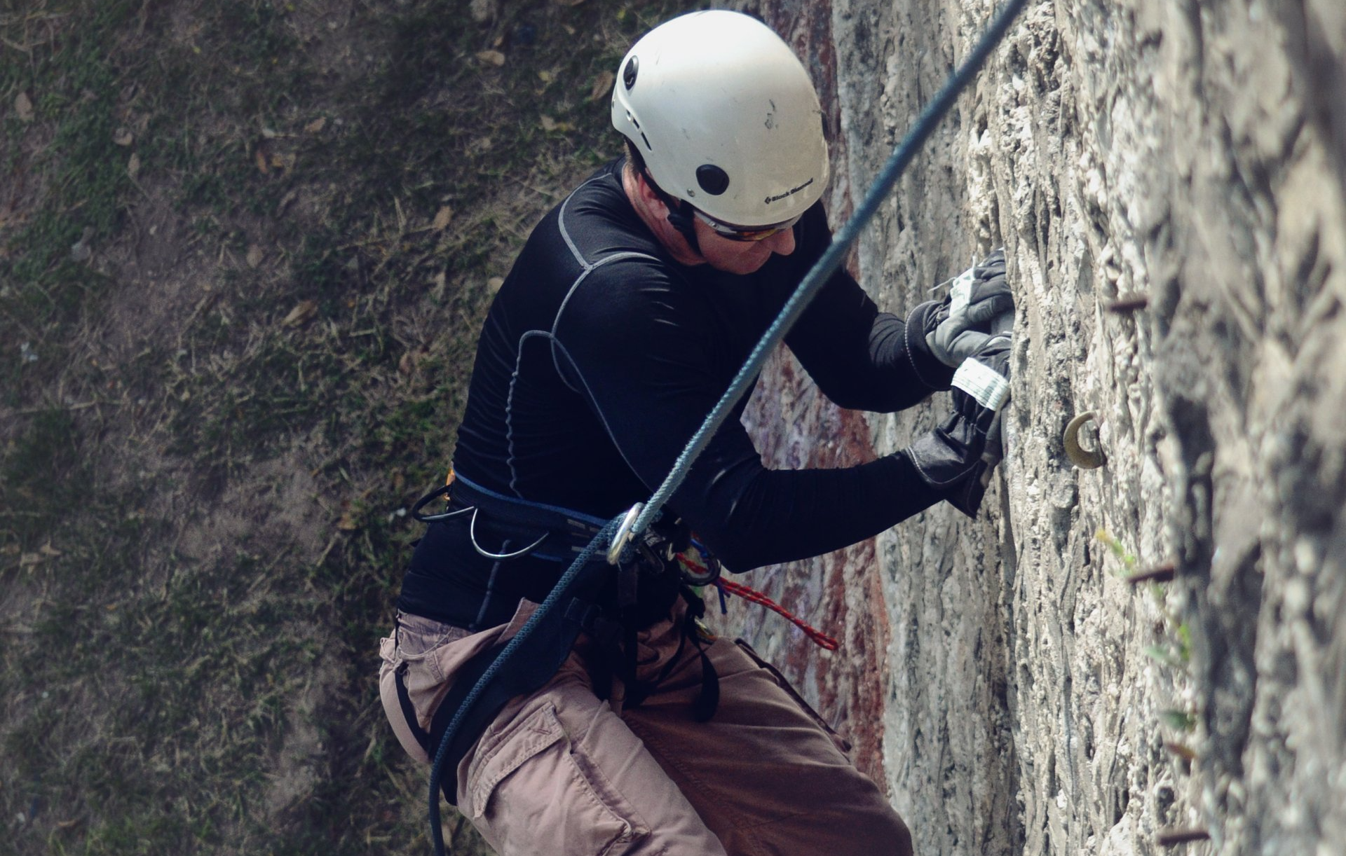 A man wearing a helmet is climbing a rock wall