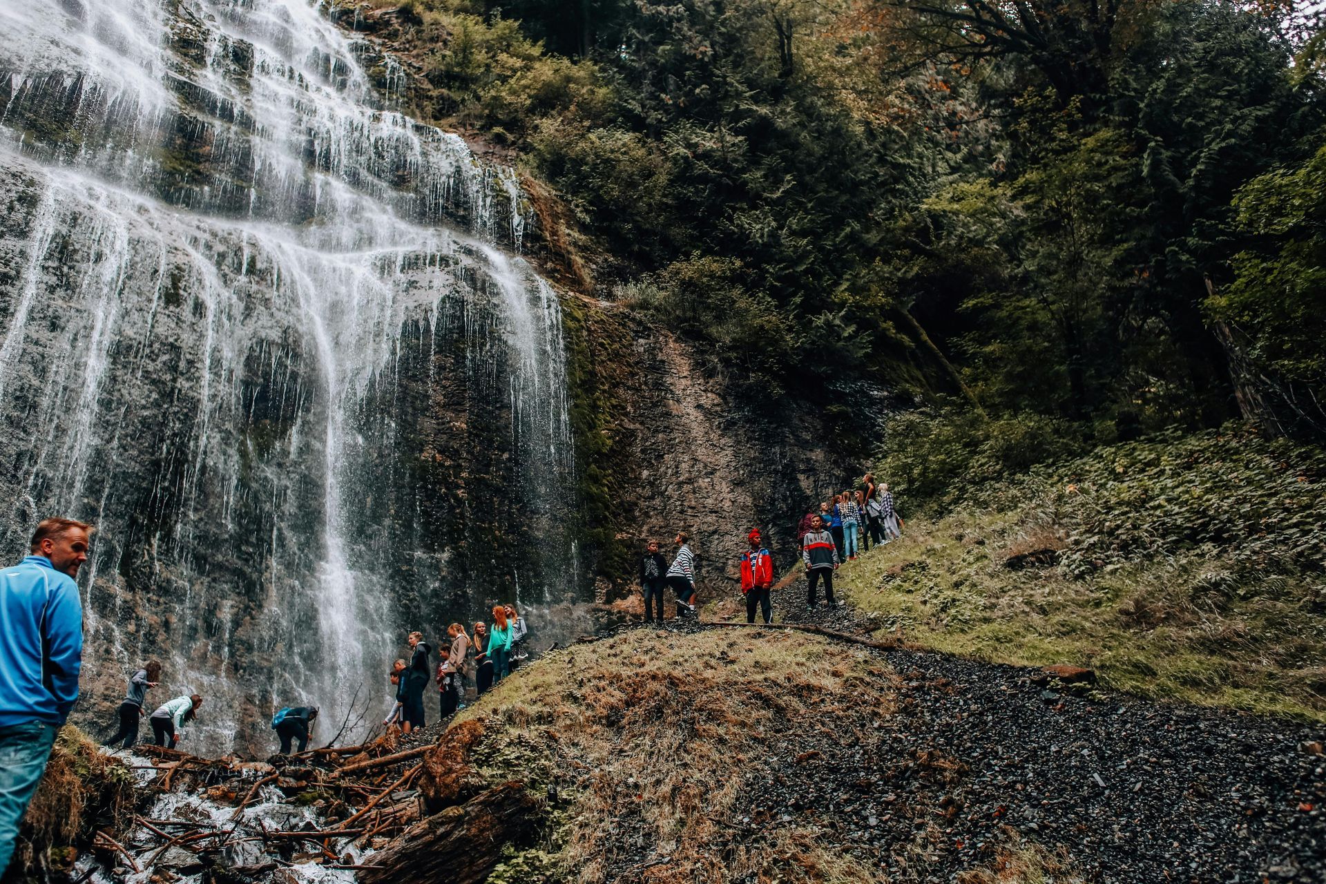 A group of people are standing in front of a waterfall.