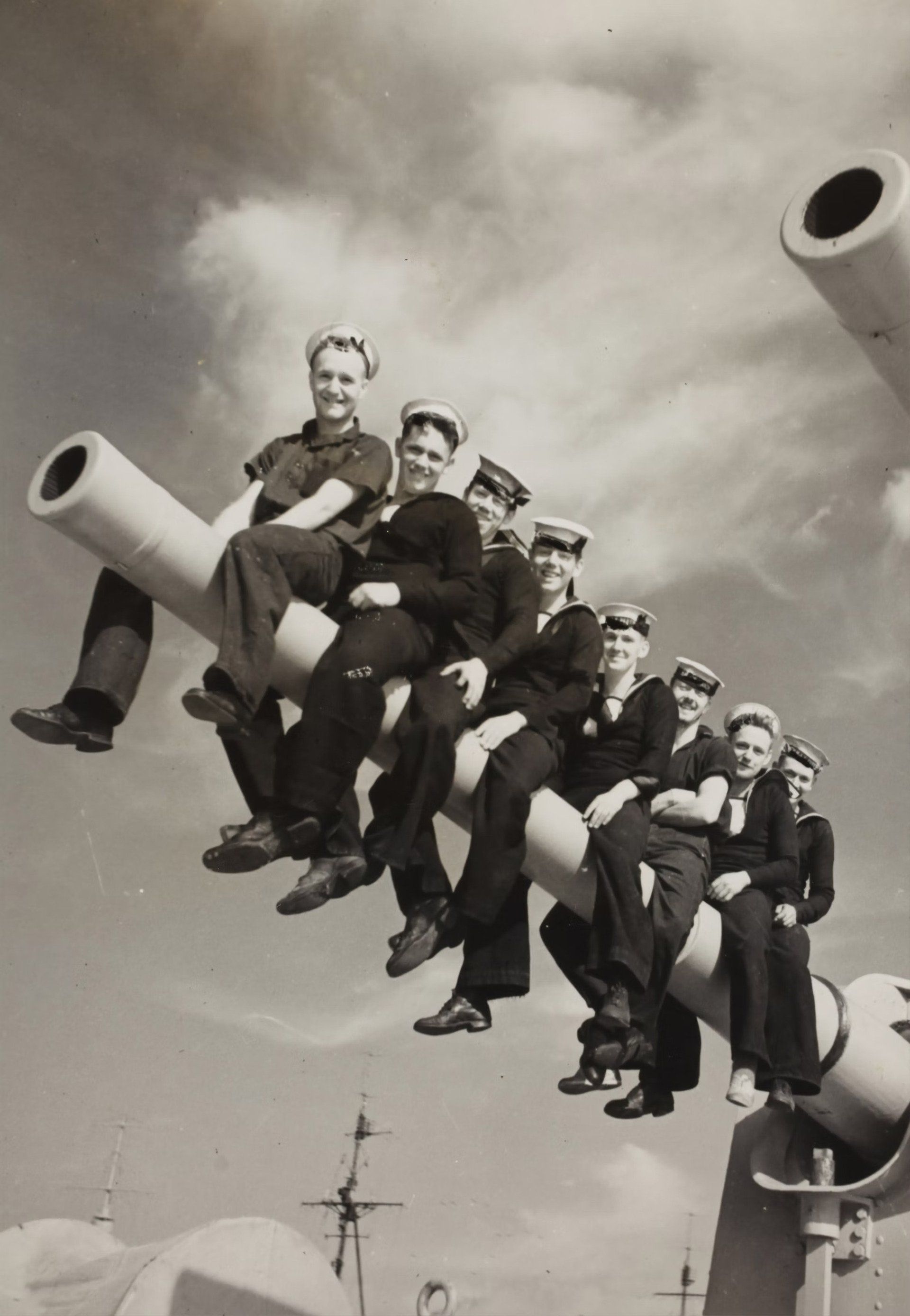A black and white photo of a group of men sitting on cannons