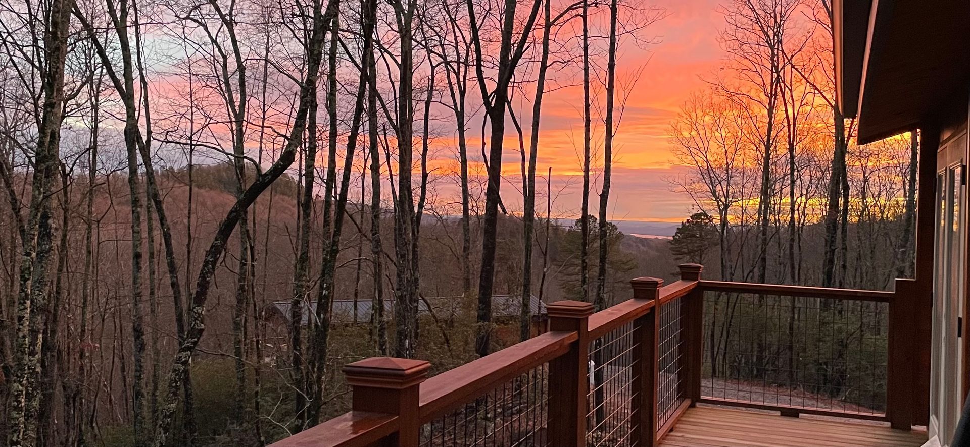 a deck with a view of a sunset over a forest .