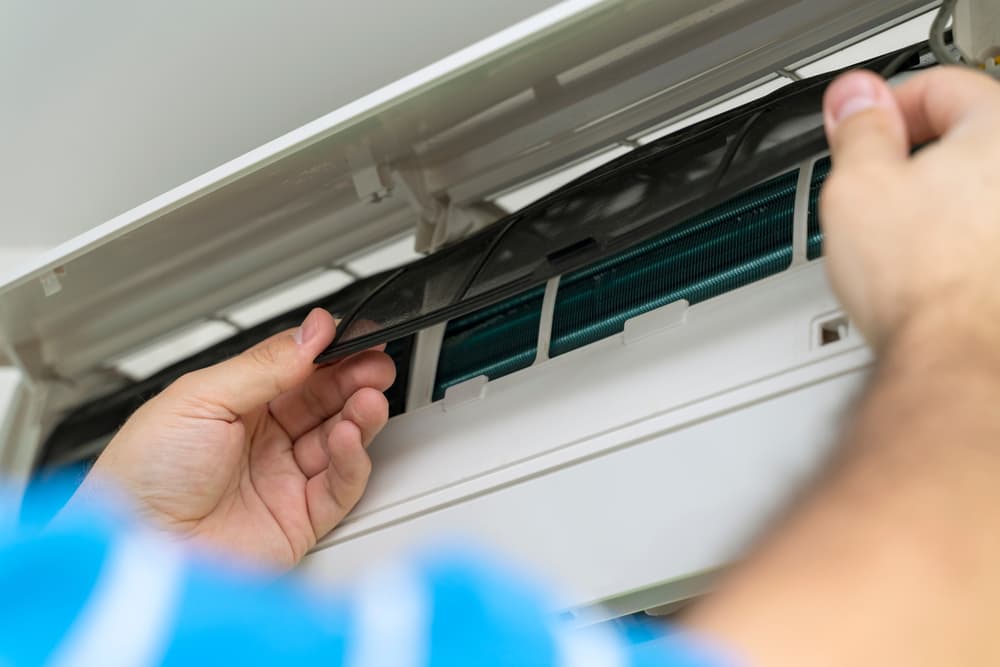A Person is Cleaning an Air Conditioner With a Brush — Action Air N Elec in Forest Glen, QLD