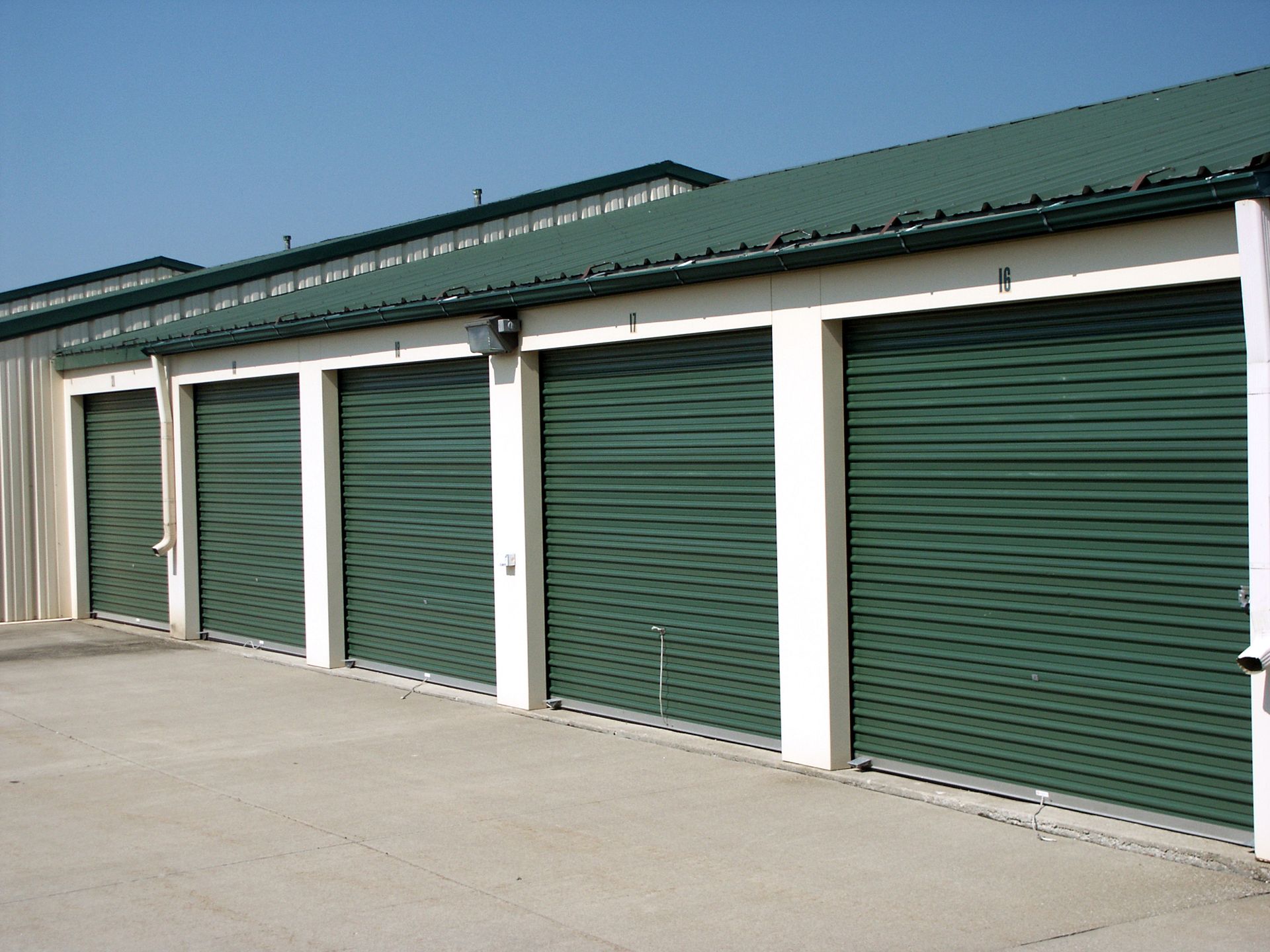A storage unit with open yellow door, filled with various boxes, furniture, and other belongings.