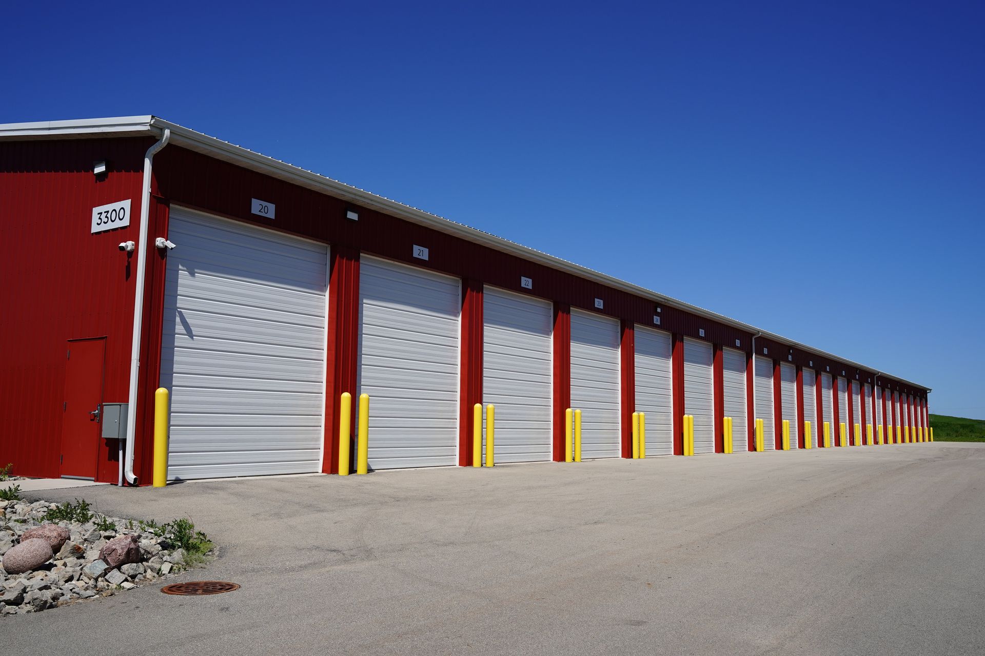 Red storage units with white doors, blue sky background.