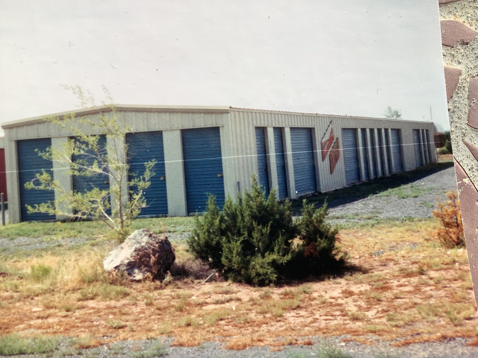 Covered RV storage units under a long metal awning, with storage units to the left.