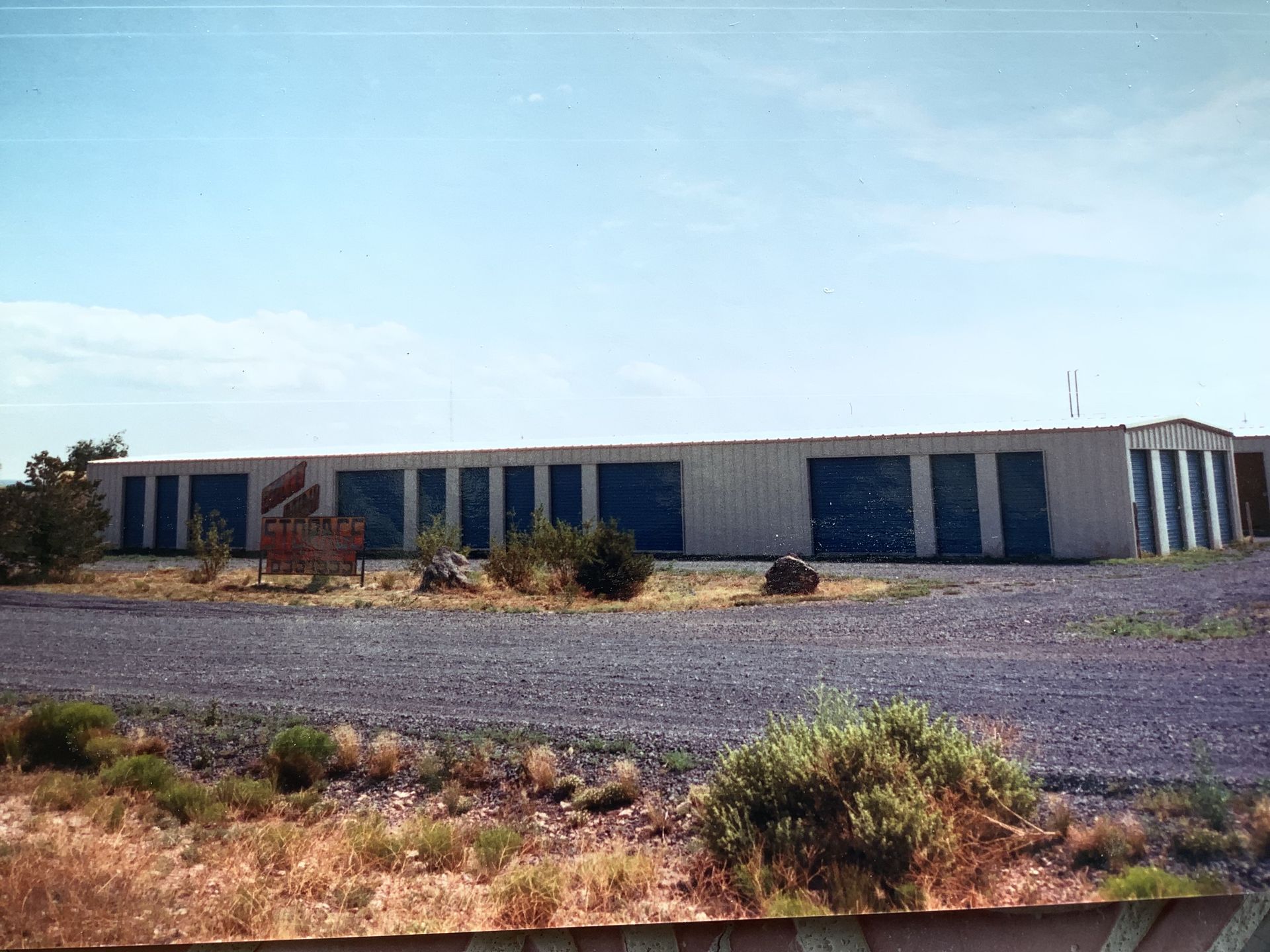 Car in a garage with closed garage doors on either side, under a gray, overcast sky.
