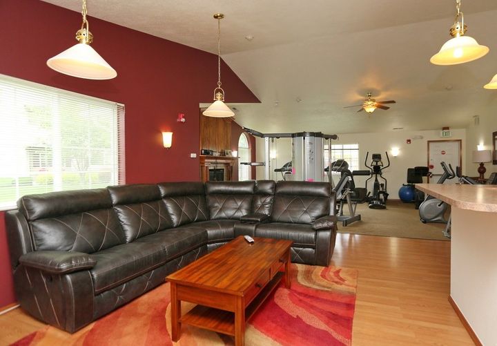 Leather sectional sofa in a living area with a red wall, and gym equipment visible in the background.