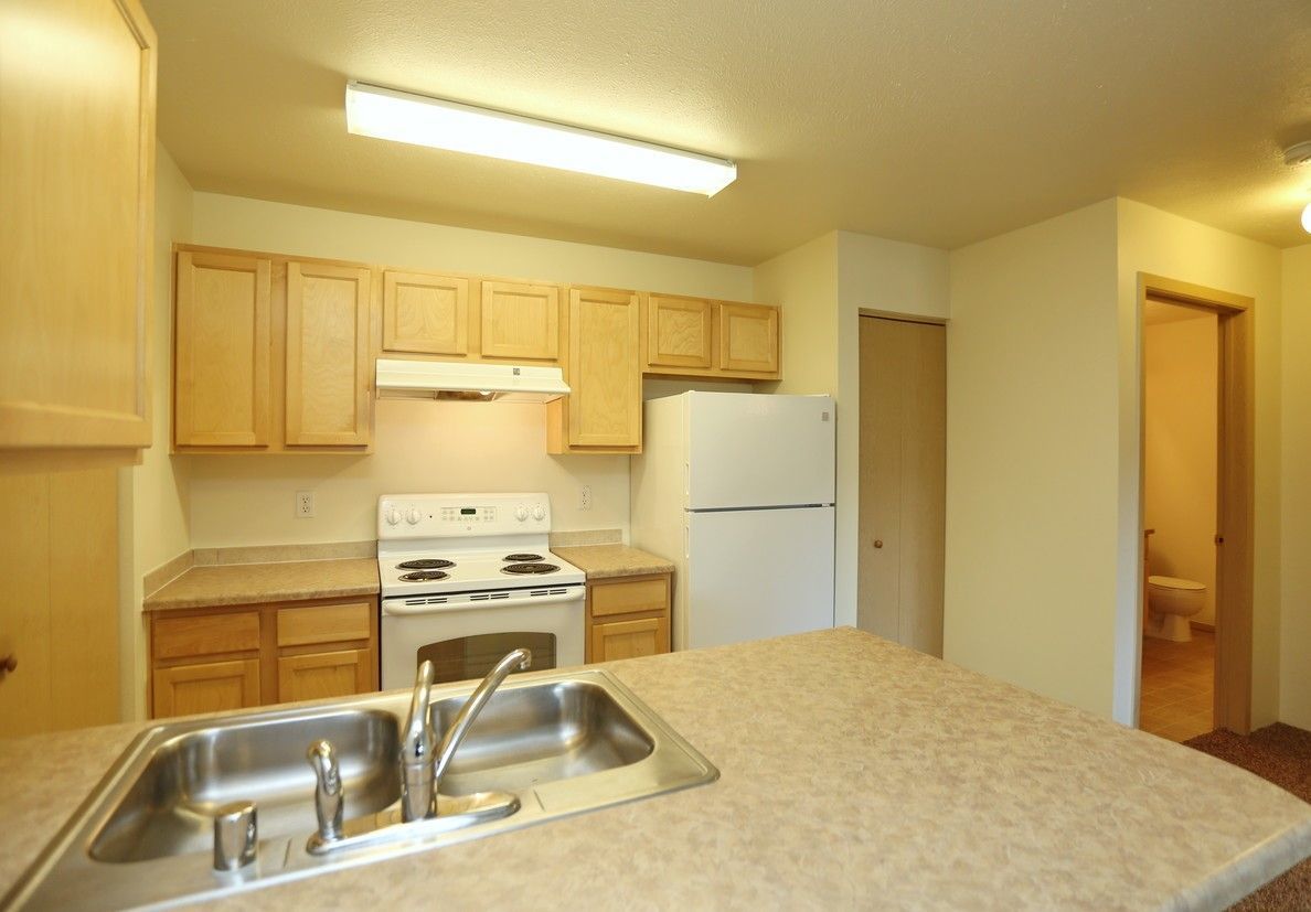 Kitchen with light wood cabinets, white appliances, and a sink in the island counter.