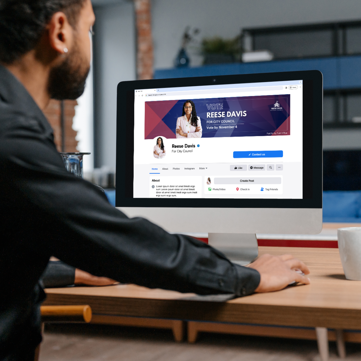 A man is using a computer with a facebook page on the screen